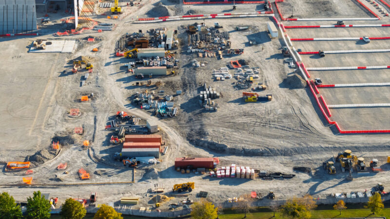 Large industrial construction site with heavy equipment and materials during development process