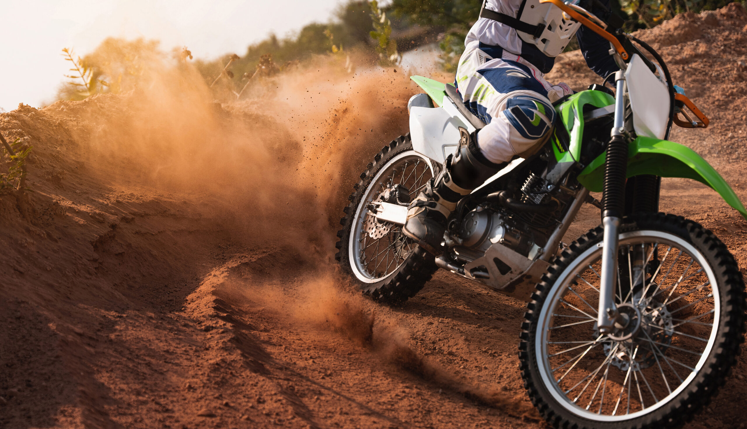 Young man practice riding dirt bike.Splashing sand