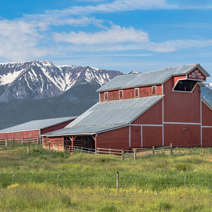 Iconic wooden red barn in Eastern Oregon with the Cascade Mountains in the background