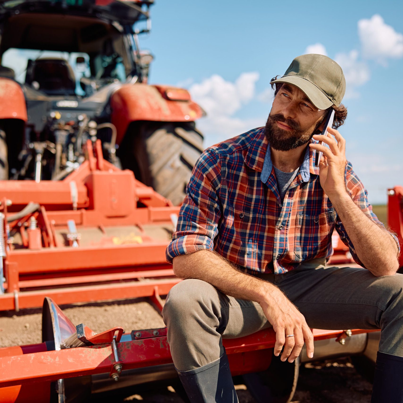 Pensive farmer making a phone call while taking a break from working in the field.