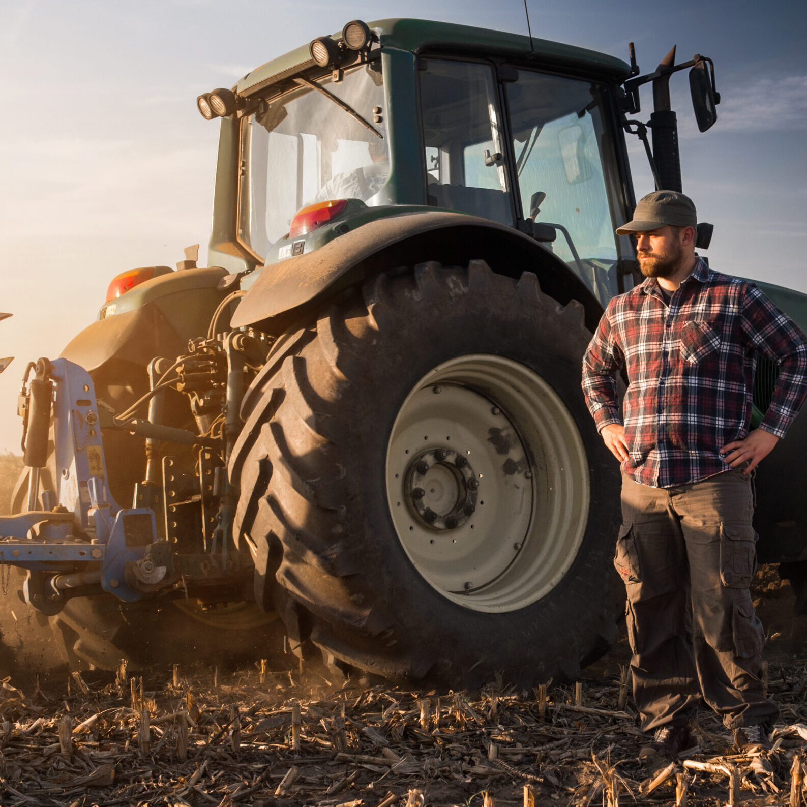 Young farmer working during the tractor plowing fields -preparing land for sowing