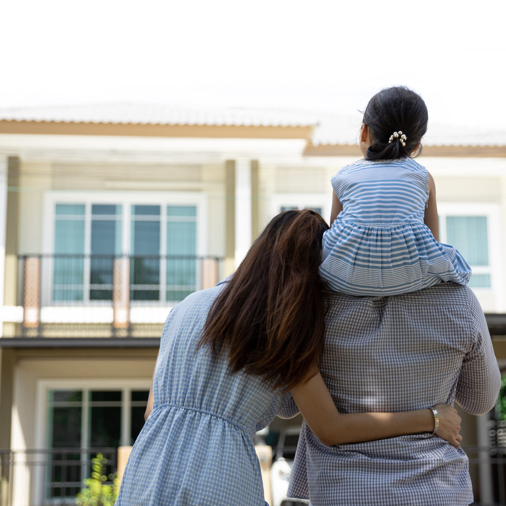 Happy Asian family. Father, mother and daughter near new home. Real estate background with copy space