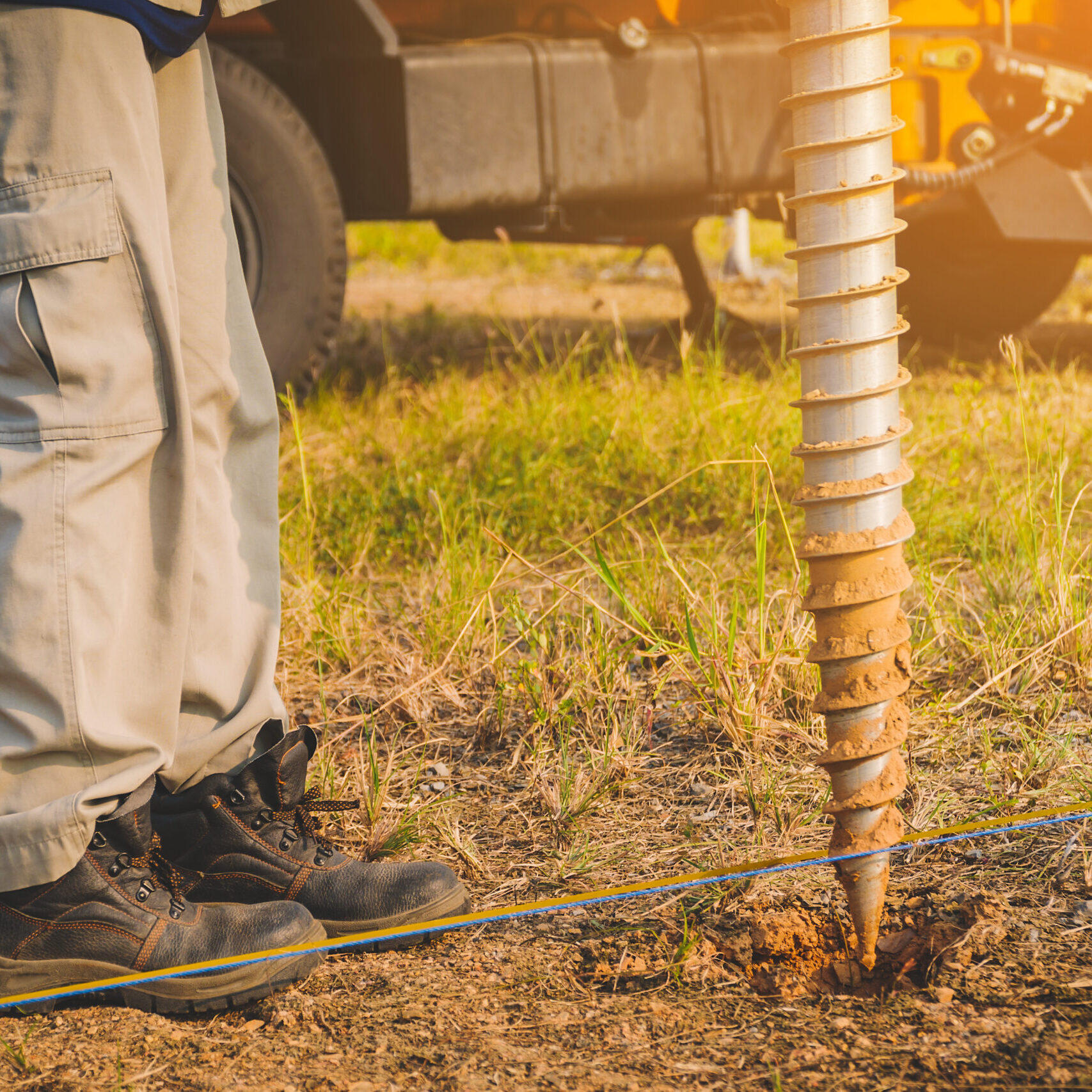 technician installing ground screw for mounting structure of solar panel at solar farm