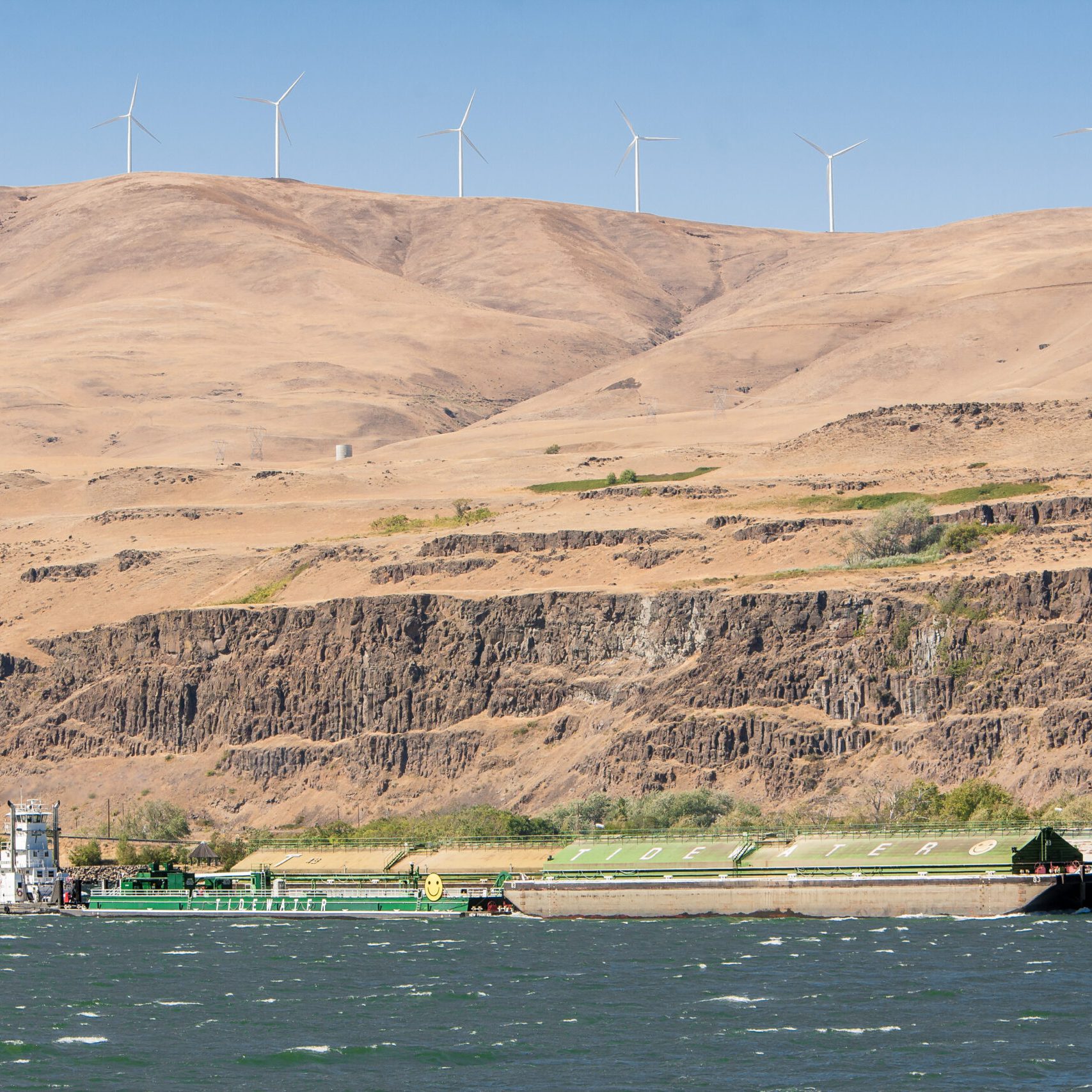 Biggs, Oregon - 9/10/2010:  A barge and tugg boat on the Columbia River near the small town of Biggs, Oregon.  Wind power generators are on the hill above the river.
