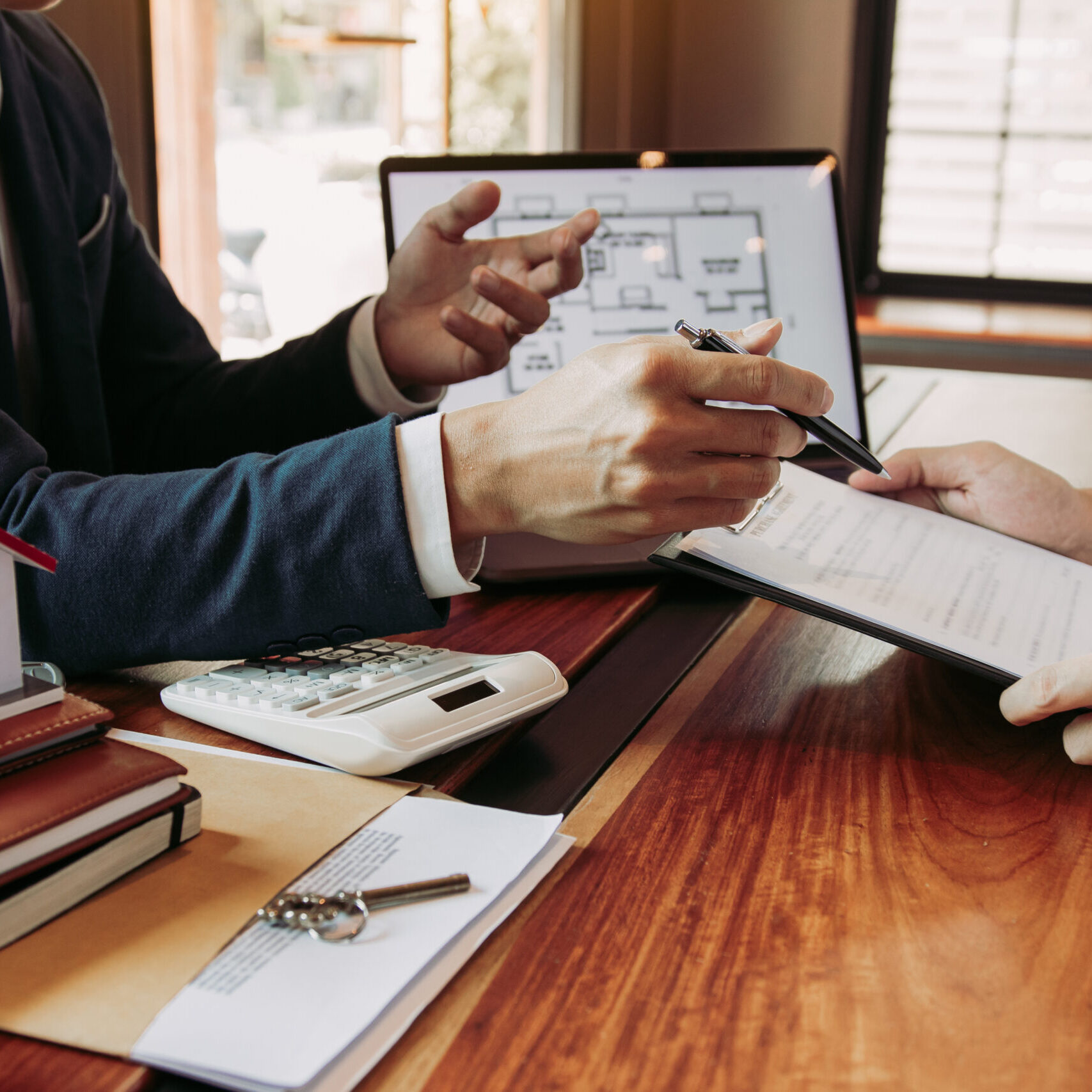 Real estate home are pointing to insurance contract signing and are explaining to customers at the office.