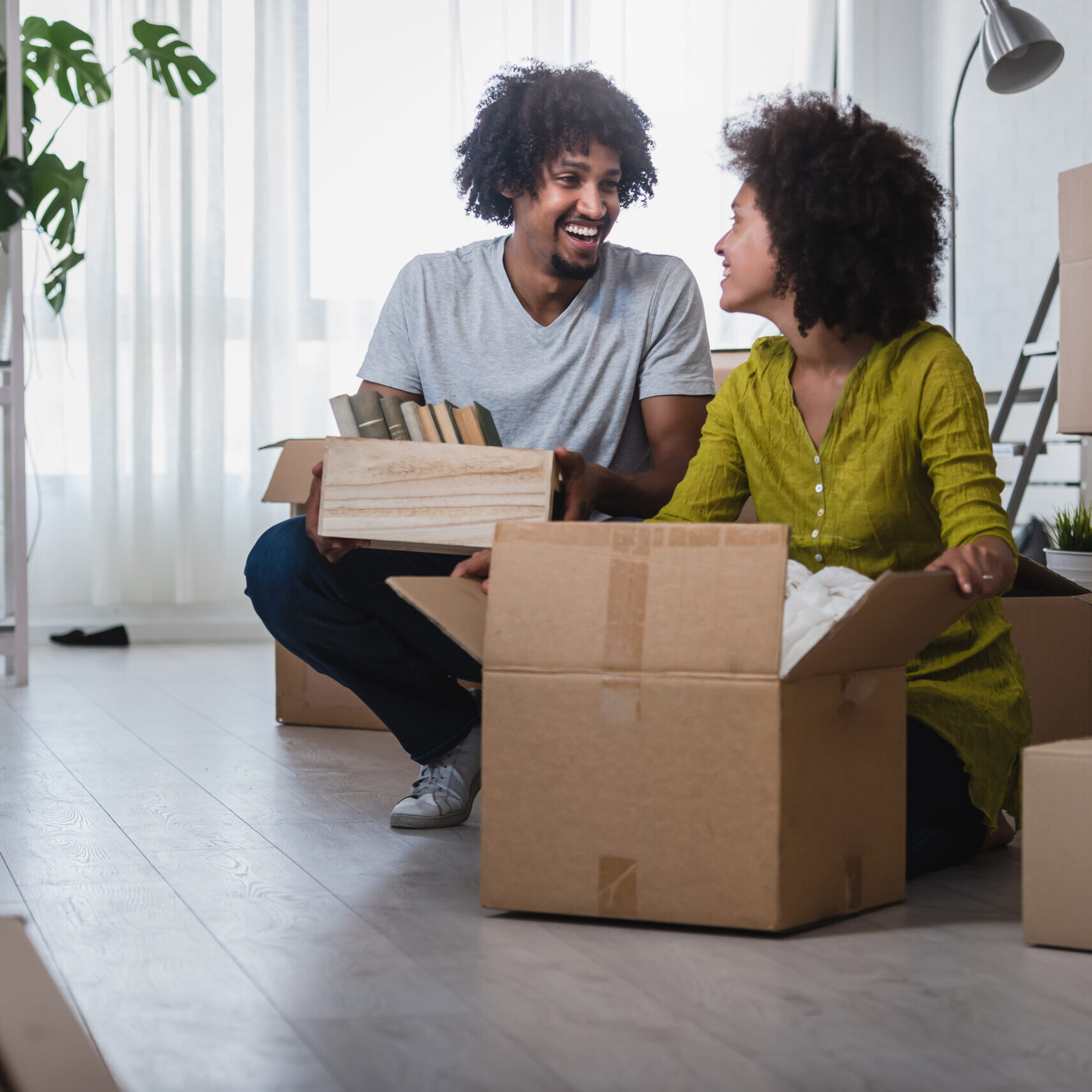 Happy playful African American couple moving in a new apartment, unpacking, moving stuff, purchase and rent property, investment concept