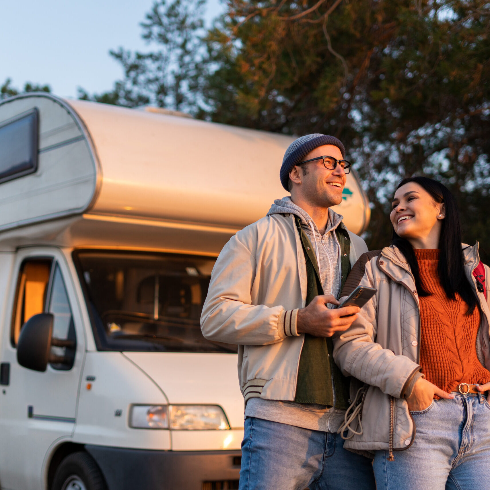 Romantic couple embracing each other while standing at the nature. Warm clothes on, autumn time. In background forest and car