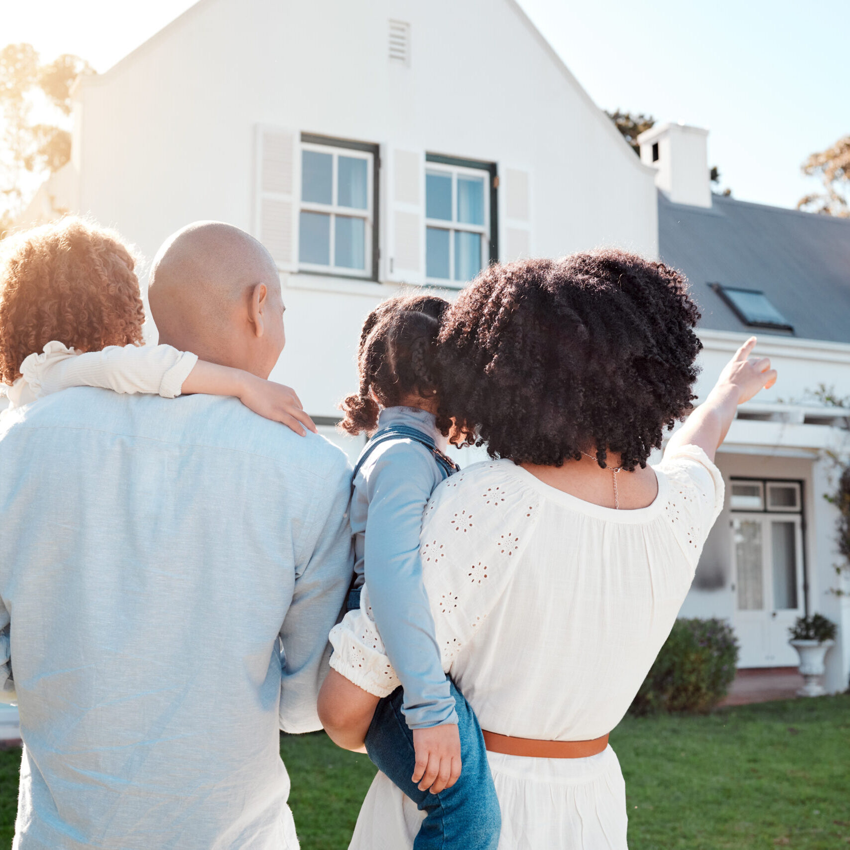Real estate, love and family in the yard of their new house bonding and spending quality time together. Mortgage, luxury property and back of young mom, dad and children standing by their modern home.