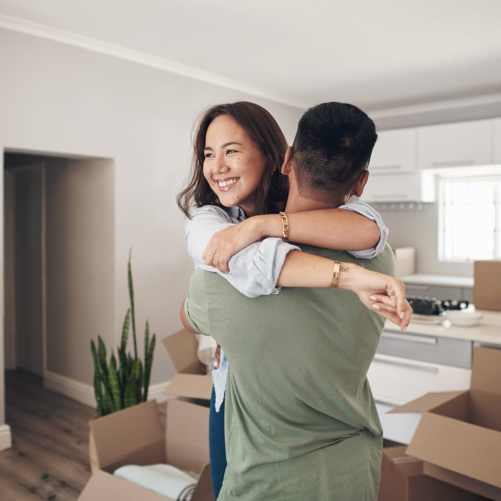 Property, happy couple moving into their new home and boxes in living room. Happiness or smiling, mortgage or homeowners and people hugging celebrating with their new house or apartment together.