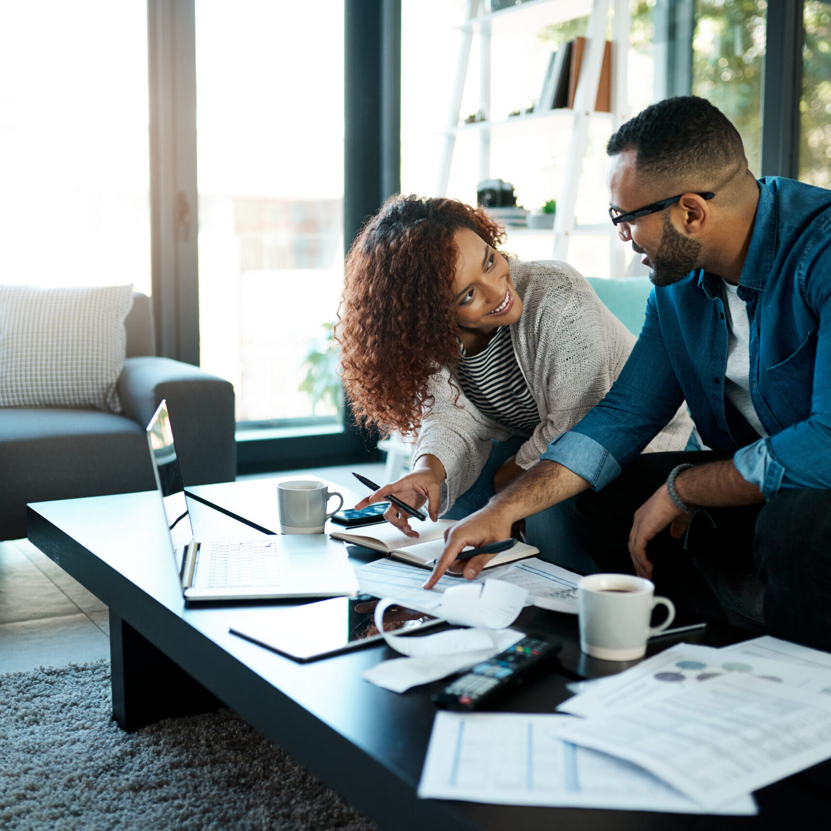 Couple with budget planning, bills and accounting of home, people with notes to pay loan and mortgage debt. Tax paperwork, man and woman happy with financial review of spending, income and savings.