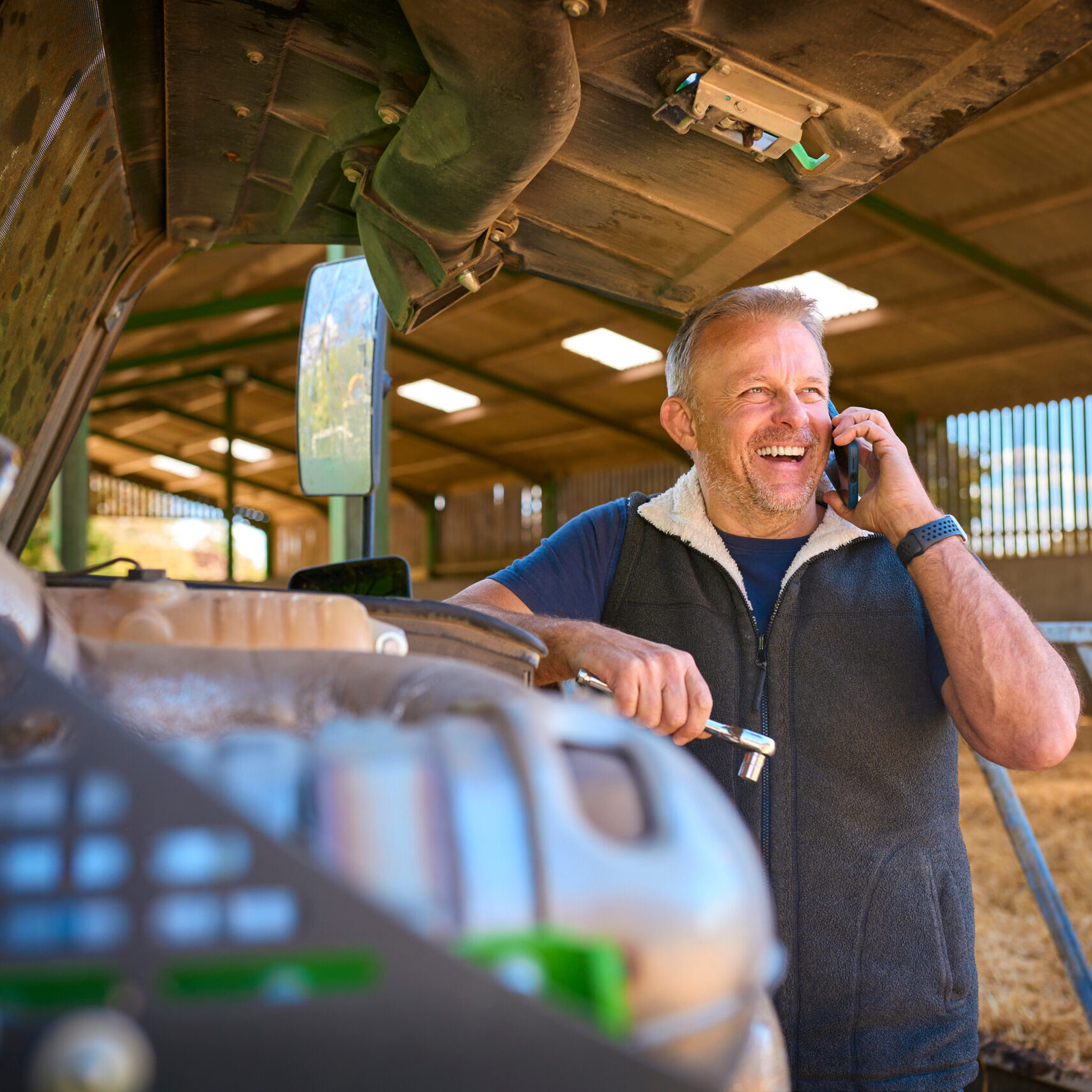 Close Up Of Mature Male Farm Worker On Phone Trying To Fix Machinery