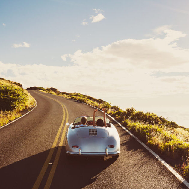Happy Couple Driving on Country Road in Classic Vintage Sports Car